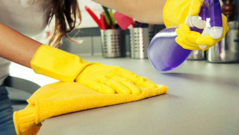 cropped image of a woman wiping kitchen counter