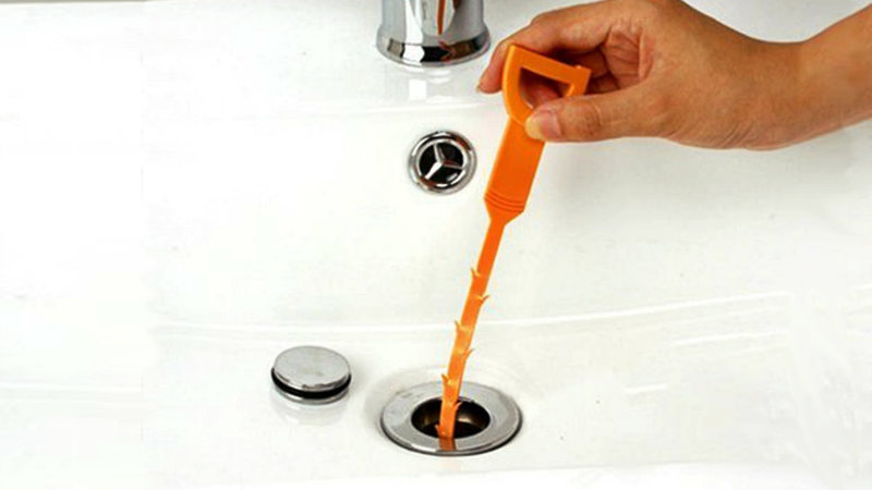 a man using the snake tool to unblock shower drain