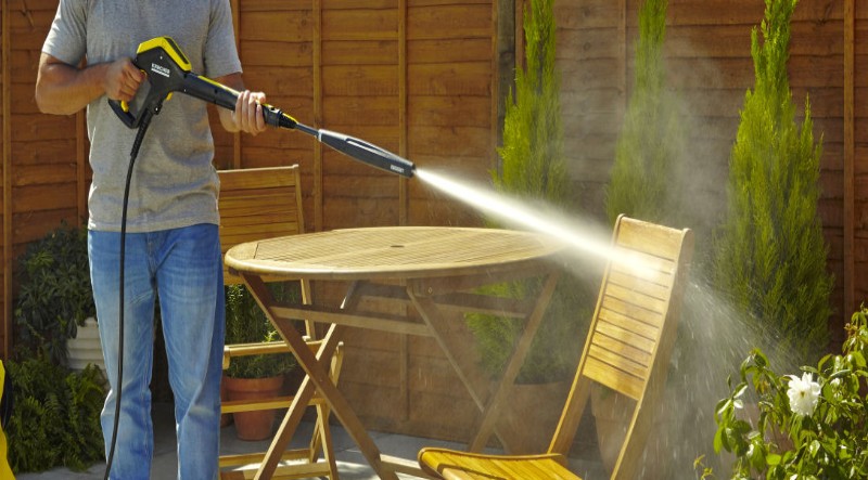 a man washing garden furniture with water