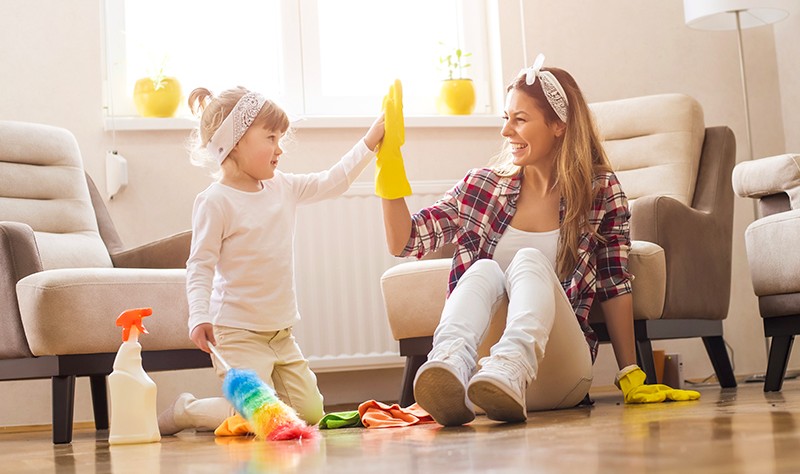 a school age kid helping her mother in dusting their house