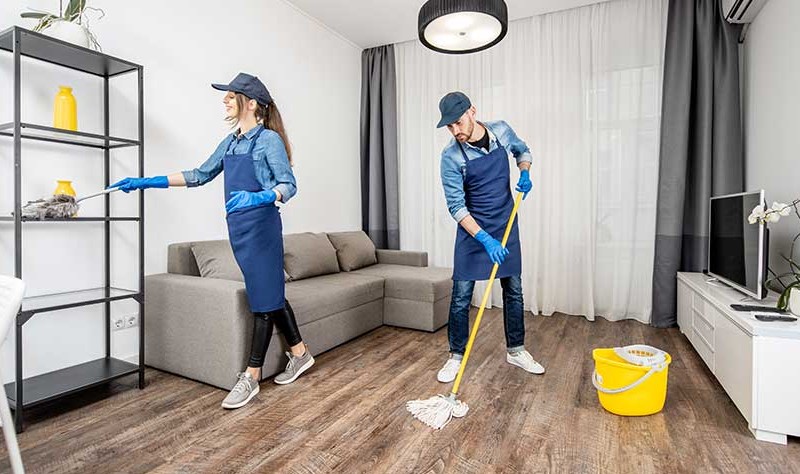 a young boy moping the floor and a woman dusting a rack