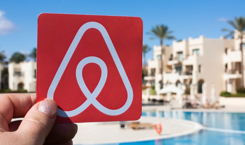 Cropped image of a woman holding Airbnb logo in hand
