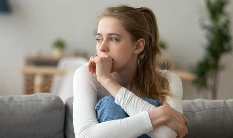 an anxious woman is sitting inside of her house