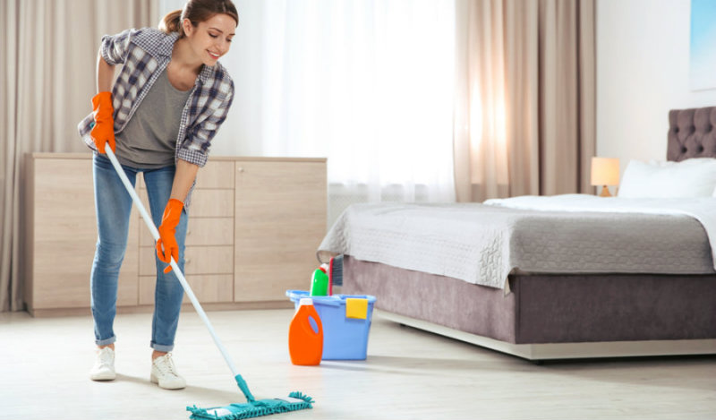beautiful young woman happily mopping the bedroom floor