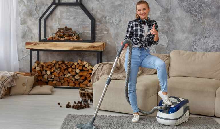 Woman in blue jeans and check shirt holding pipe of vacuum cleaner and put her leg on vacuum cleaner