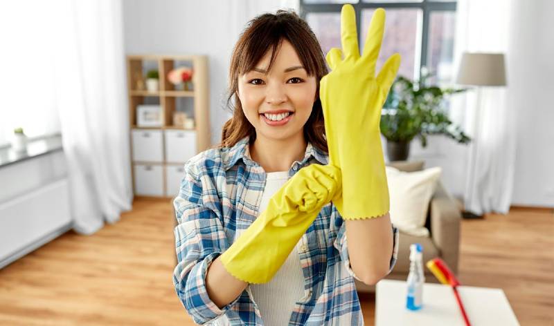 Woman in yellow gloves and check shirt inside a room