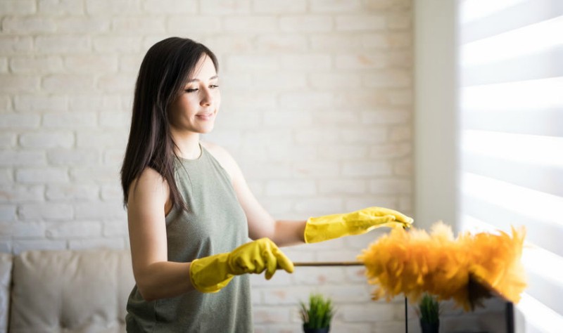 young woman dusting her house