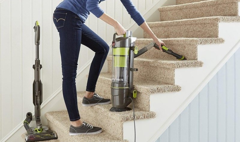 cropped image of a young woman vacuuming the carpeted stairs