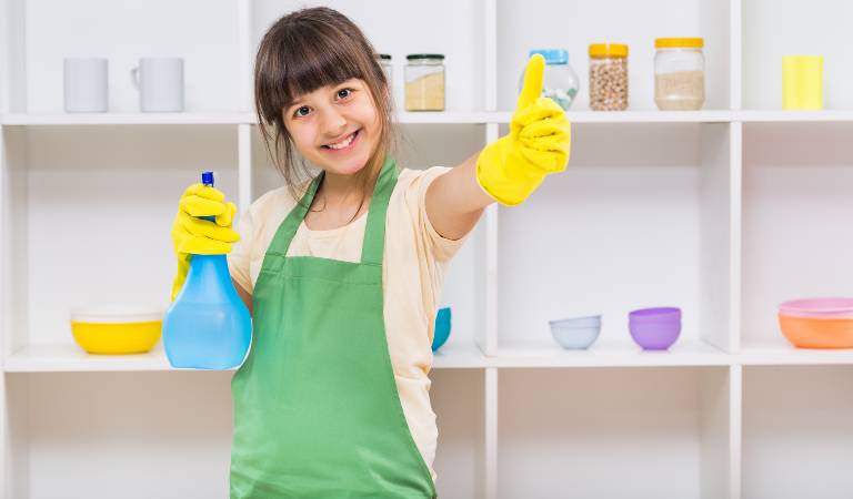 A happy little girl showing thumbs up holding a blue bottle in her hand