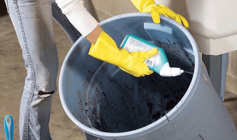 a woman spreading some solution on a trash can