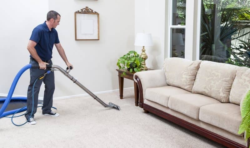young man vacuuming the carpet