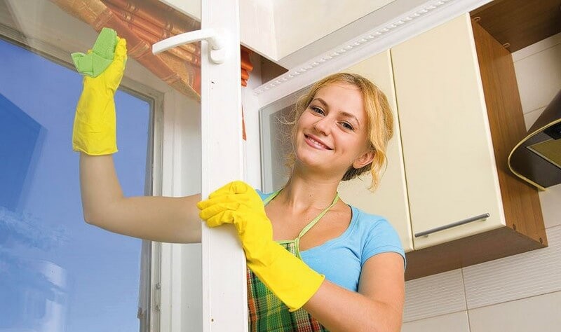 beautiful young woman wiping the window glass with a cloth wipe
