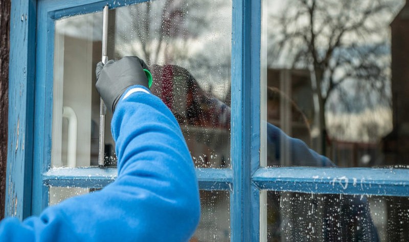 cropped image of a man wiping moisture droplets from the window glass