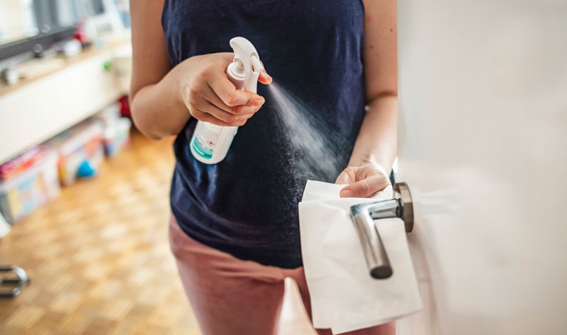 cropped image of a woman disinfecting a door knob