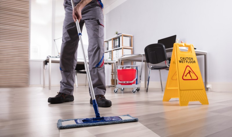 A young man is moping the floor