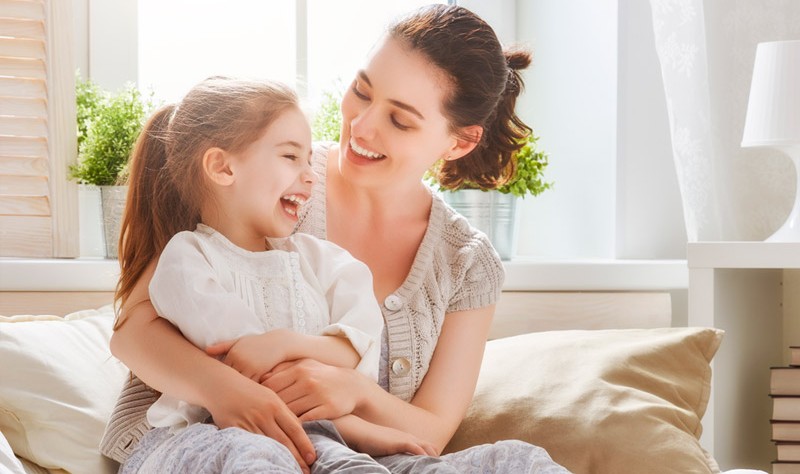 young mother and her daughter sitting inside of their house