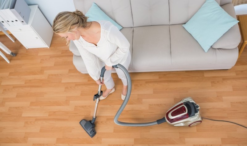 young woman vacuuming the floor with a vacuum cleaner
