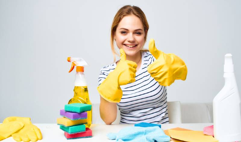 Woman in yellow gloves thumps up and some tools are spread on table