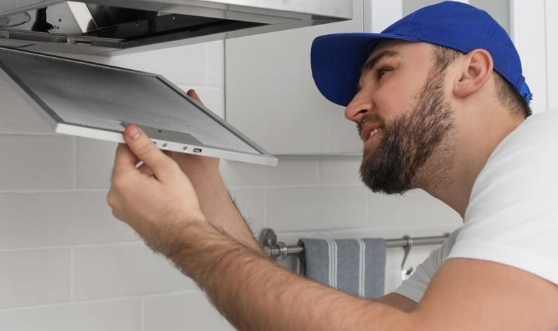 young woman wearing blue cap fixing a Range Hood Filters