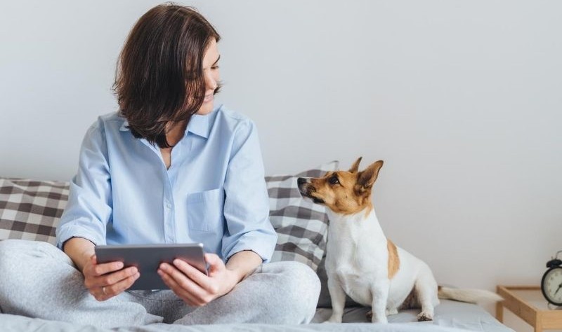 young woman sitting on a bed with her dog