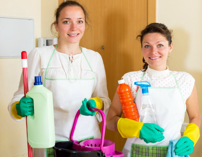two ladies standing with bucket and bottles in hand