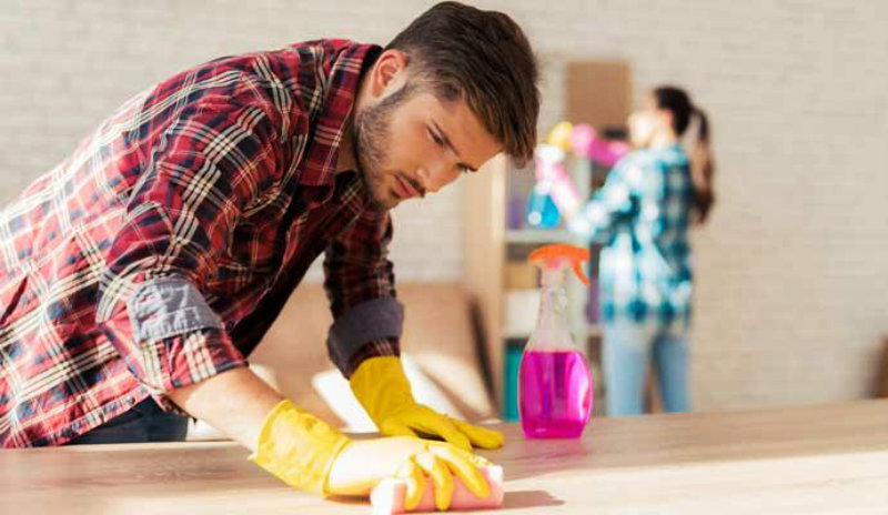 young man wearing rubber gloves wiping the table