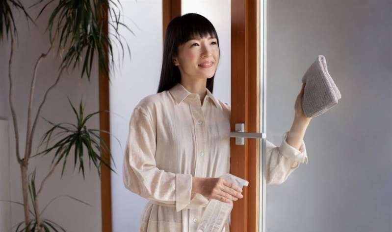 Marie Kondo wiping the window glass with a cloth rag