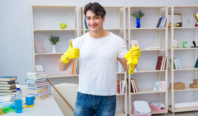 Man in white t-shirt, blue jeans and yellow gloves standing and thumps up