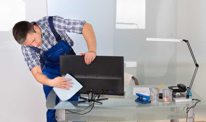 young professional wiping a computer system with a cloth