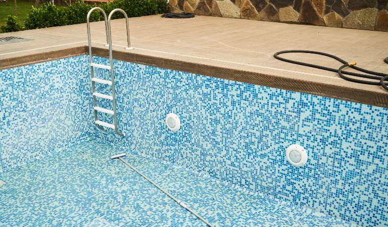 Empty swimming pool with metal ladder.