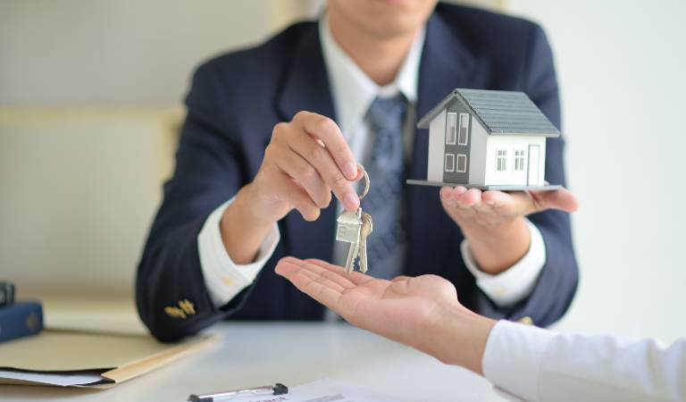 Man in black suit is giving key to a lady