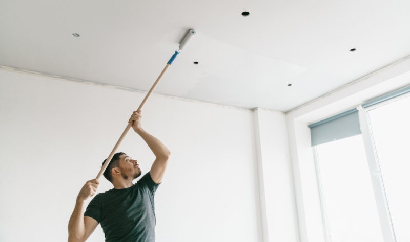 a young man dusting his roof with a dusting stick
