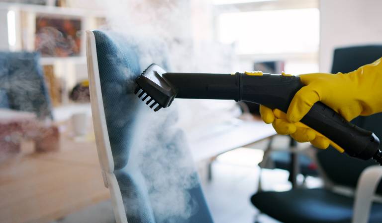 Hand in yellow glove steam cleaning on chair