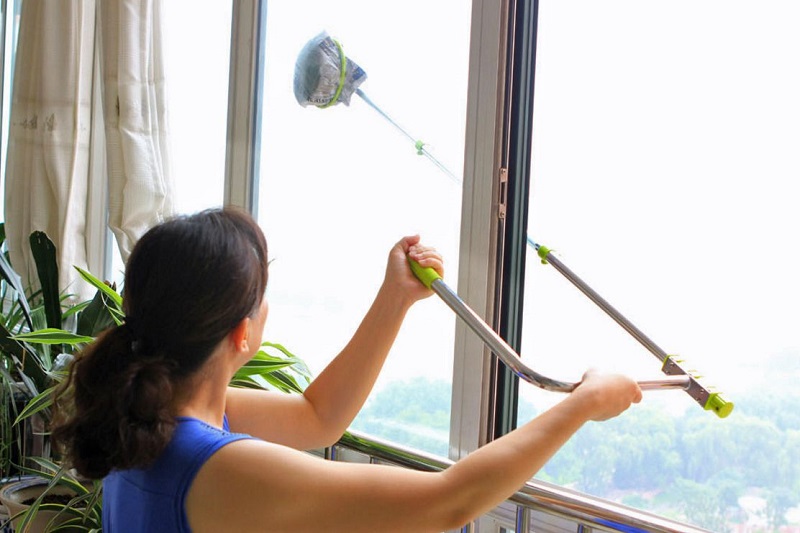 young woman wiping the window glass with a mop