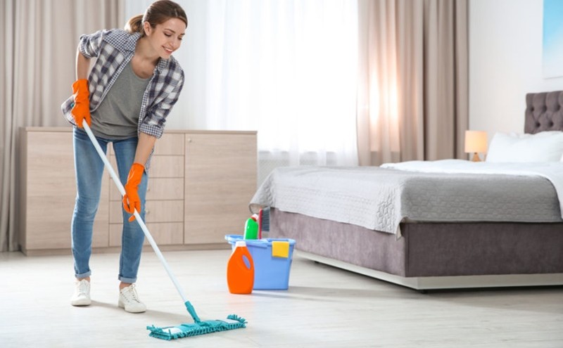 young woman moping her bedroom floor with a cloth mop