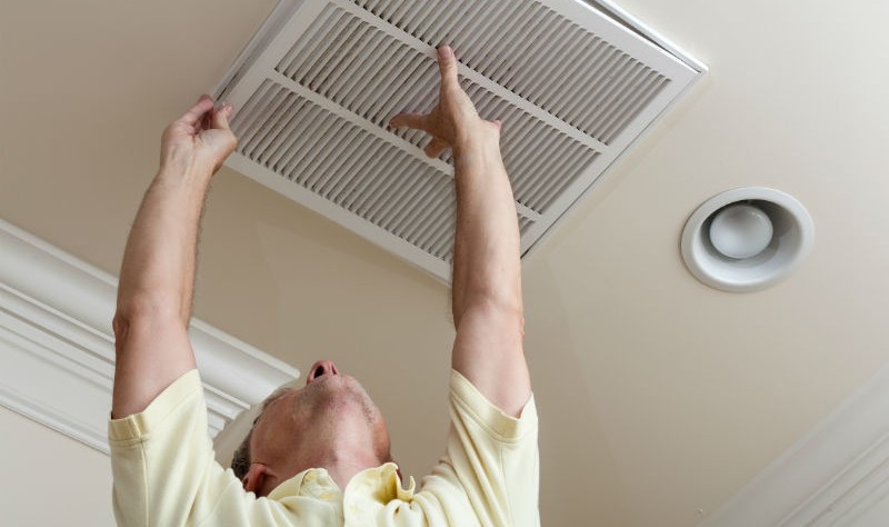 a young man is trying to fix a air duct cover