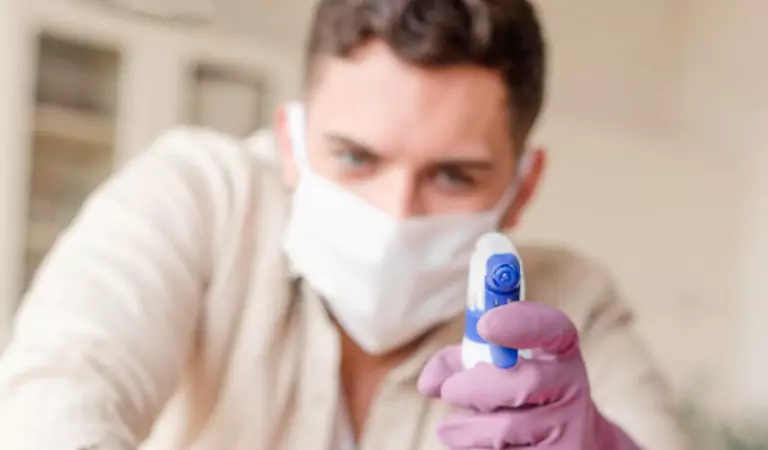young man wearing mask on face with a cleaning spray
