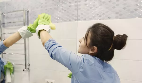 woman cleaning a bathroom mirror