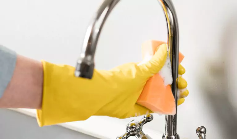cropped picture of a person cleaning a sink faucet