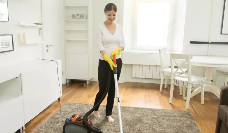 Young woman vacuuming a carpet