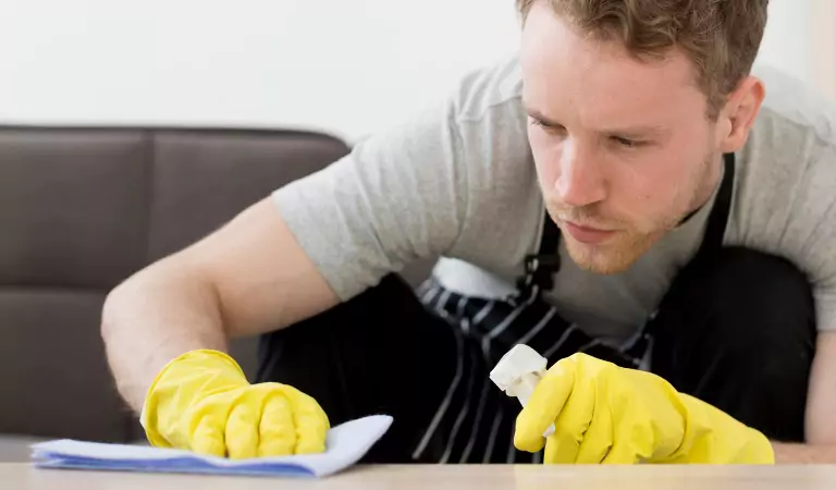 young man disinfecting a household surface