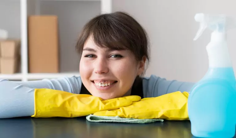 woman with yellow gloves and a cleaning spray at front