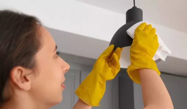 woman cleaning light fittings inside of her house