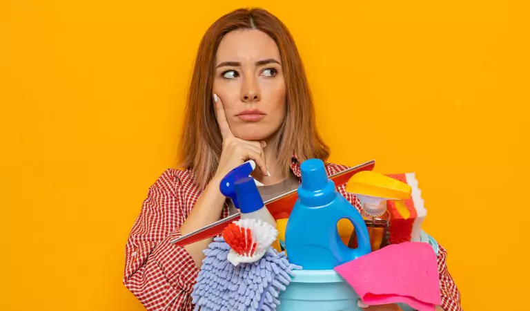 woman with a bucket of cleaning products looking confused