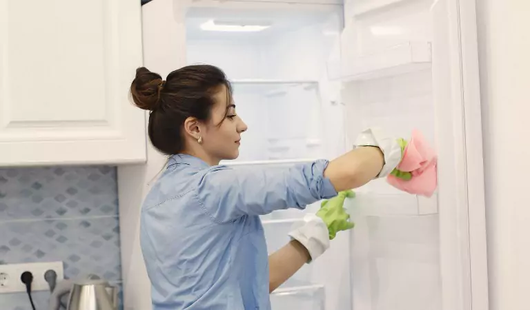 young woman cleaning a fridge