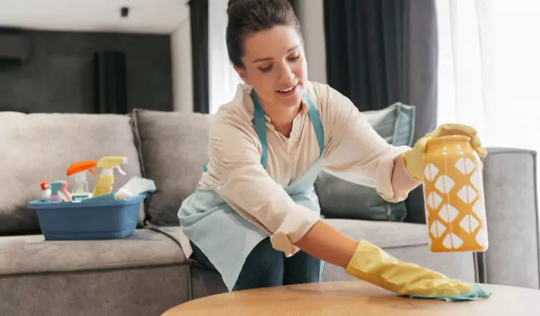 young woman sprucing up her house and some cleaning essentials at the back