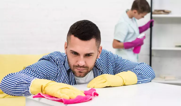 young man wiping a surface and woman at the back cleaning a surface
