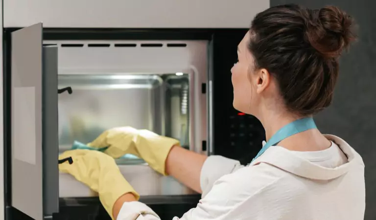 young woman cleaning an oven