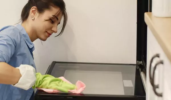 woman cleaning an oven with a cloth mop