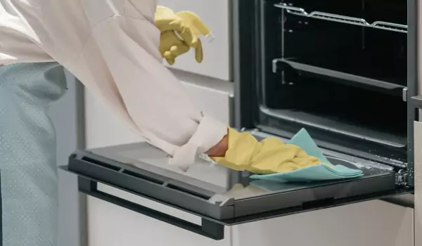 cropped picture of a person cleaning an oven